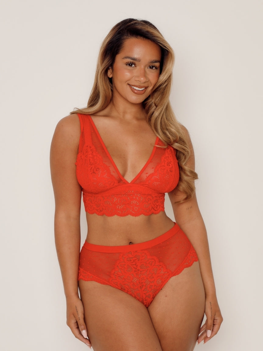 Woman wearing a red lace lingerie set against a plain background