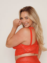 Woman wearing a red lace outfit against a plain background